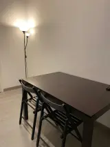 Dark wooden dining table with two black folding chairs and a floor lamp in the Interior Apartment